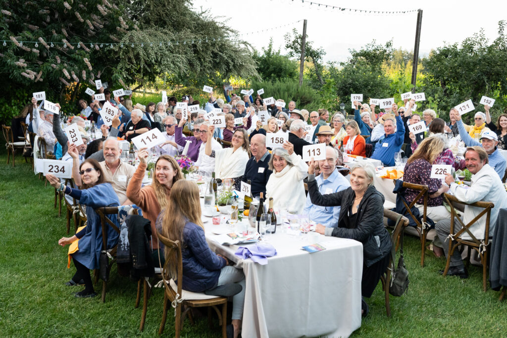 Guests of Our Long Table holding up bidder numbers