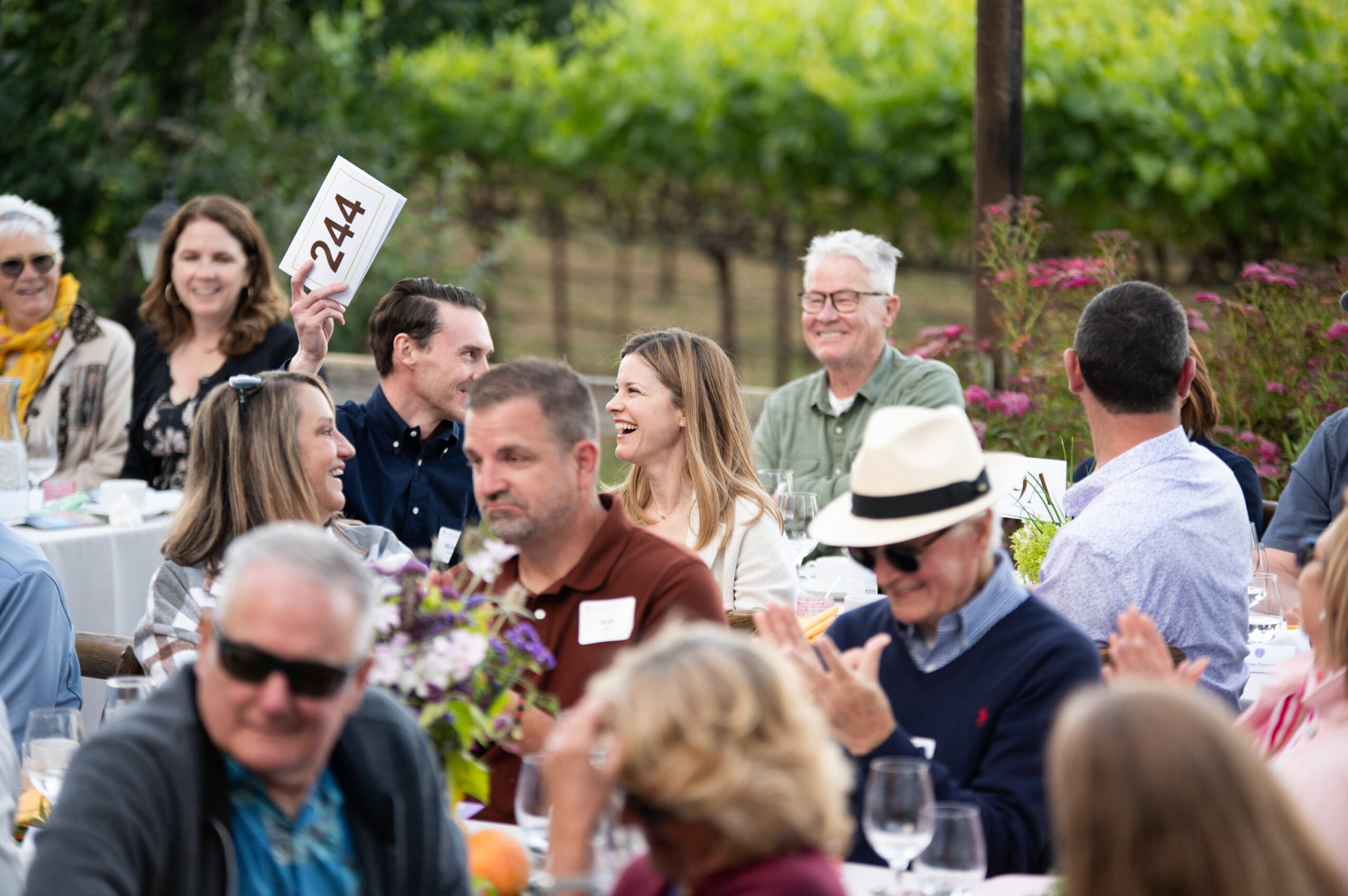 Our Long Table guests laughing and holding up bid numbers during the auction