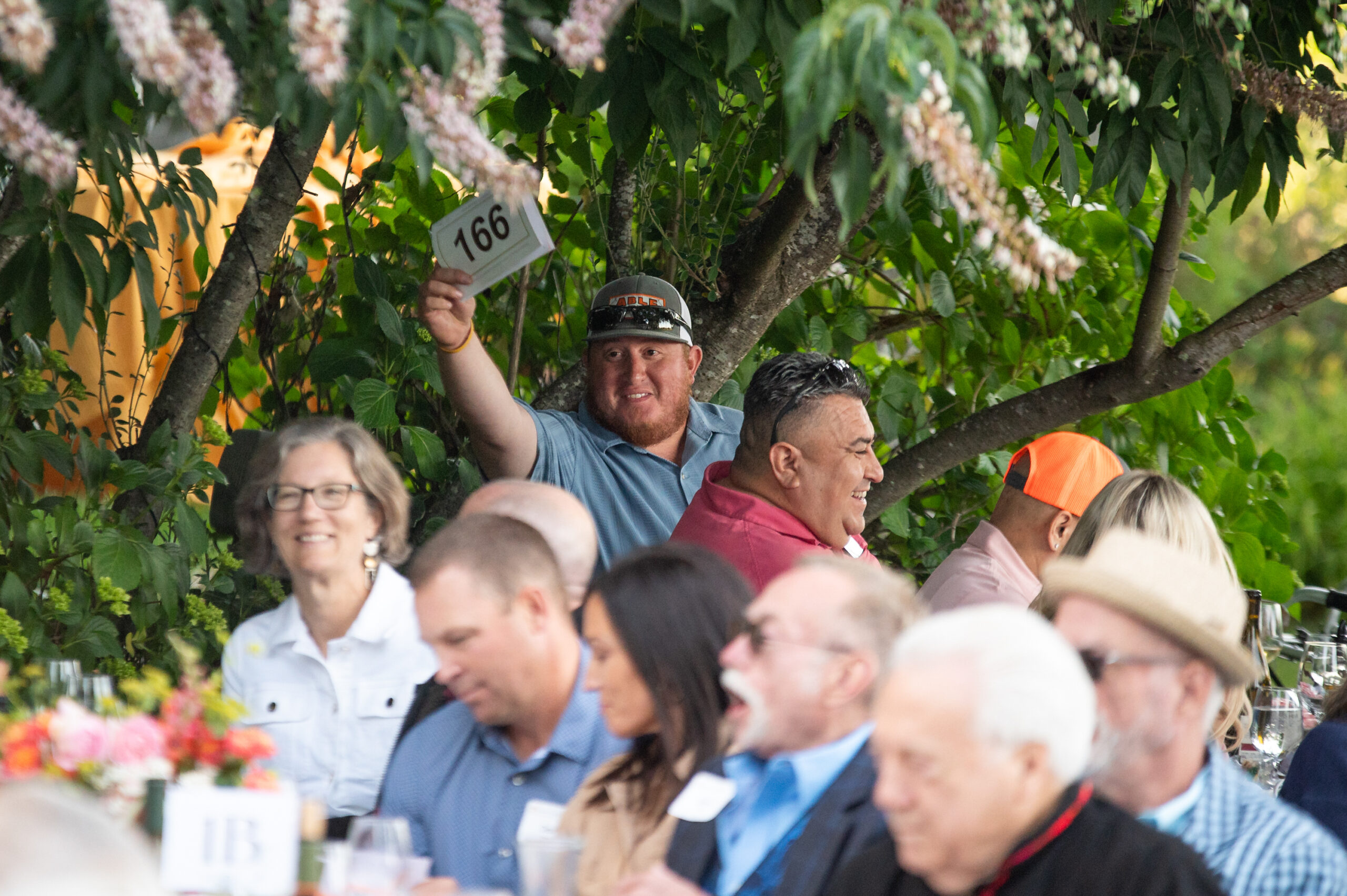Our Long Table guests laughing and holding up bid numbers during the auction