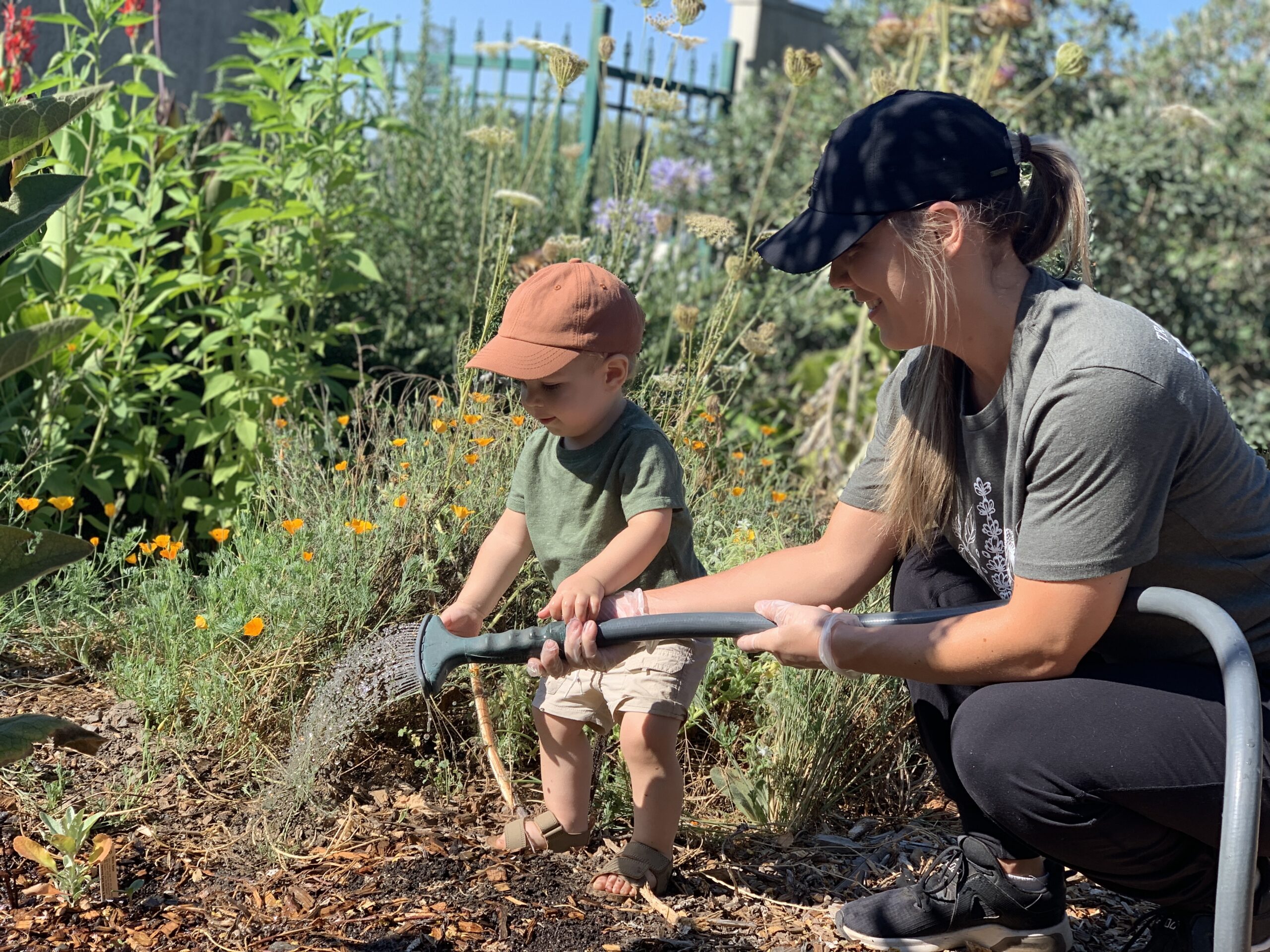 Mother and child watering plants in the Food For Thought garden