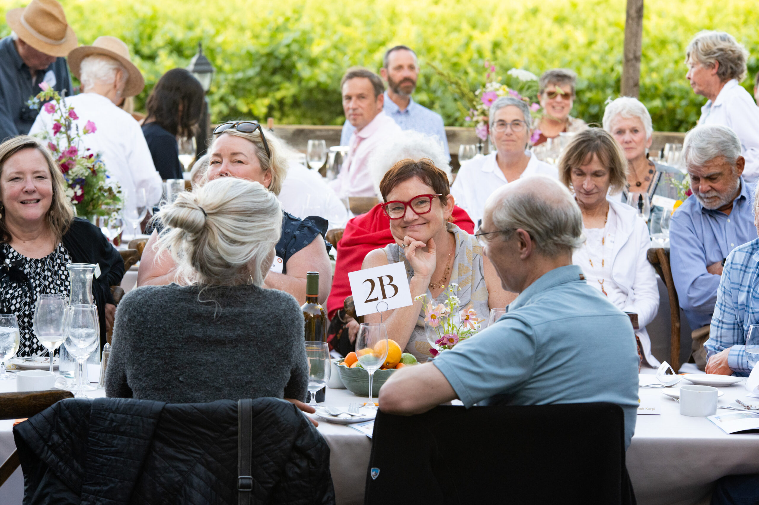 Amongst dinner guests at a table, a woman smiles at the camera