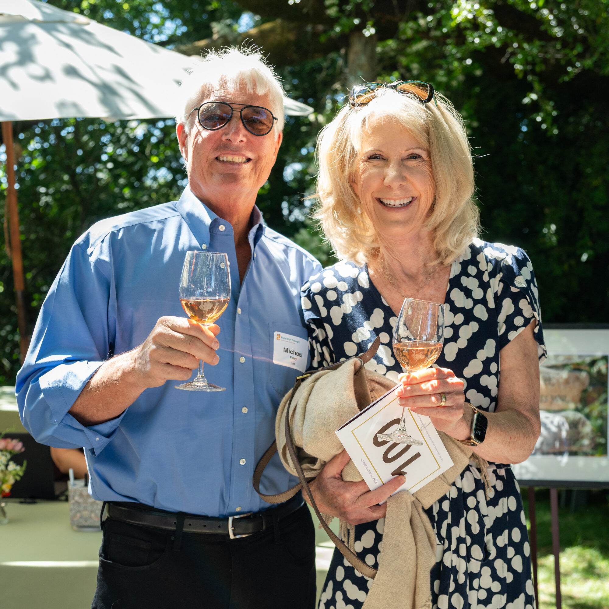 A couple holding wine glasses smile at the camera